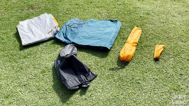 From left to right: rainfly (white), tent body (blue), carry bag (black), poles (longer yellow carry bag), stakes and guylines (shorter yellow carry bag).