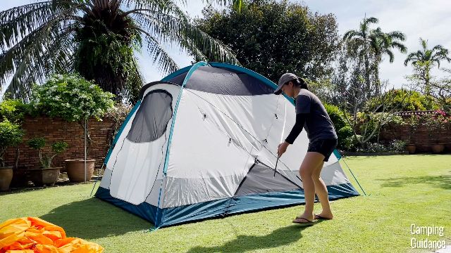 This is a picture of me securing one of the black poles of the REI Base Camp 6. The other 3 poles (2 blue, 1 black) have already been set up.