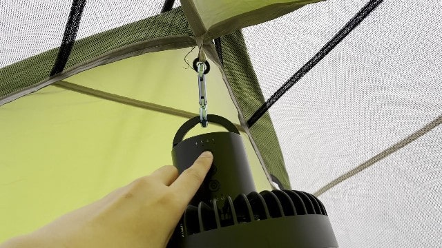 The Nitecore NEF10 Fan hanging at the top of a tent with its handle and separate carabiner.